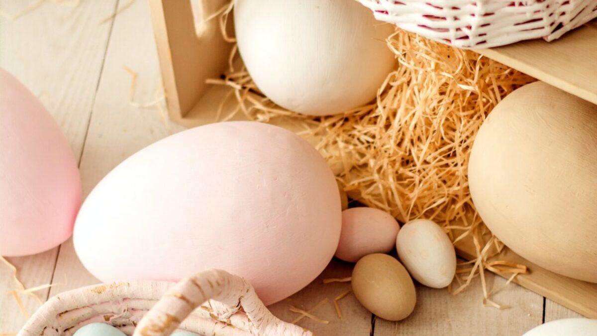 Verschieden große Eier verteilt in einem Korb und einer Holzkiste mit Stroh